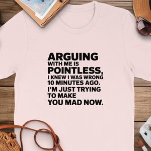 May include: A pink t-shirt with a black graphic that reads "Arguing with me is pointless, I knew I was wrong 10 minutes ago. I'm just trying to make you mad now."