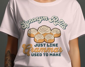 Puede incluir: Camiseta rosa con un diseño gráfico de rollos de canela y el texto "Synonym Rolls Just Like Grammar Used To Make".