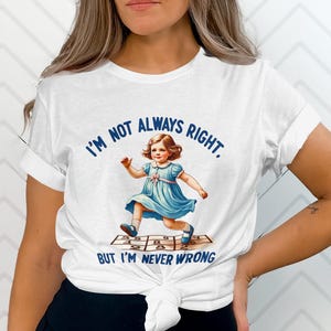 May include: White t-shirt with a graphic of a girl playing hopscotch. The text on the shirt reads "I'm not always right. But I'm never wrong."