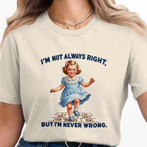 May include: A white t-shirt with a blue graphic of a girl playing hopscotch. The text on the shirt reads "I'm not always right, but I'm never wrong."