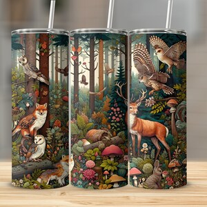 May include: Three stainless steel tumblers featuring a forest scene design. The tumblers depict a variety of woodland animals, including owls, a fox, a deer, and a rabbit. The background is a lush green forest with trees, leaves, and mushrooms.