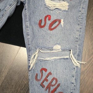 🎨 Descrizione prodotto:  
Pezzo audace e d’impatto per chi ama distinguersi: pantaloni in jeans dipinti a mano con il volto iconico del Joker accompagnato dalla celebre frase "Why so serious?". Ogni dettaglio è realizzato a mano con passione, rendendo questo capo una vera opera d’arte da indossare.