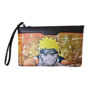 Può includere: Una pochette rettangolare con cinturino da polso, caratterizzata da un pannello superiore marrone scuro e un corpo dipinto con un personaggio anime dai capelli gialli e fascia blu su sfondo arancione con calligrafia giapponese dorata.