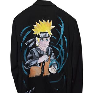 Può includere: Un blazer nero con un'illustrazione dipinta a mano del personaggio anime Naruto Uzumaki sul retro. Il personaggio ha capelli gialli a punta, una fascia nera ed è circondato da effetti energetici blu vorticosi. La firma CReation è visibile.