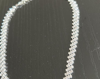 May include: A silver choker necklace with a geometric pattern of small, clear rhinestones.