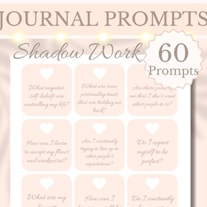 May include: A set of 60 pink journal prompts with a white heart cutout in each card. The prompts are for shadow work and include questions like "What negative self-beliefs are controlling my life?" and "Do I expect myself to be perfect?"