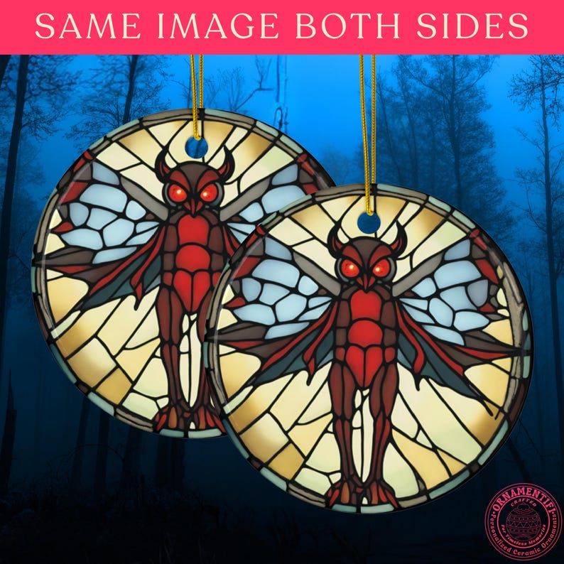 May include: Two round ceramic ornaments featuring a stained glass style illustration of a red and brown horned owl-like creature with large glowing red eyes and expansive wings. Each ornament hangs from a gold string against a dark forest background.