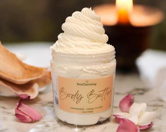 May include: A white jar of body butter with a swirl of cream on top. The jar has a label that says "BeaCharming Body Butter Handmade - Cruelty Free - SLS Free".