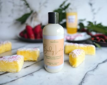 May include: A white bottle of body lotion with a black cap and a label that says "BeaCharming Body Lotion" and "Hydrating Lotion with Shea Butter and Moringa Oil". The label also says "Handmade, Cruelty Free, Gluten Free".