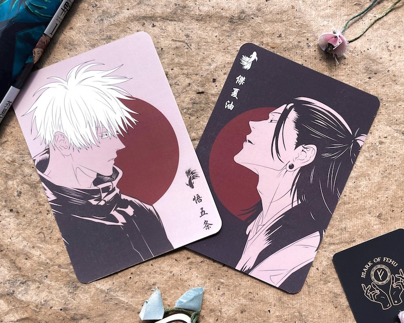 May include: Two rectangular cards with anime-style illustrations. One card features a white-haired character against a pink background with a red circle. The other card shows a black-haired character with a red circle. Japanese text is visible.