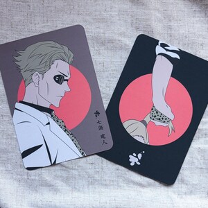 May include: Two rectangular cards with anime-style illustrations. One features a man in a white suit and sunglasses against a red circle, the other a person's arm and neck. Japanese text is visible.