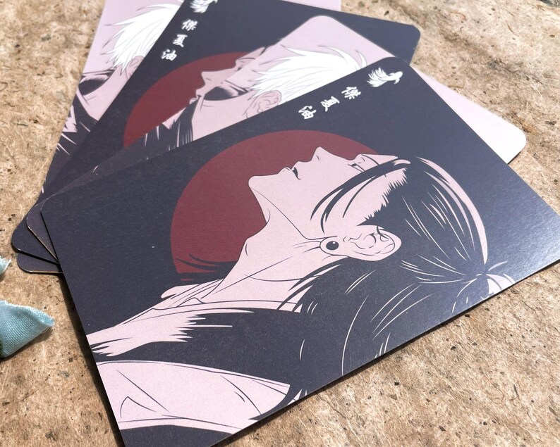 May include: A stack of black and pink cards featuring anime-style illustrations. Each card displays a profile of a person with long hair against a dark background with a red circle. Japanese text is visible.