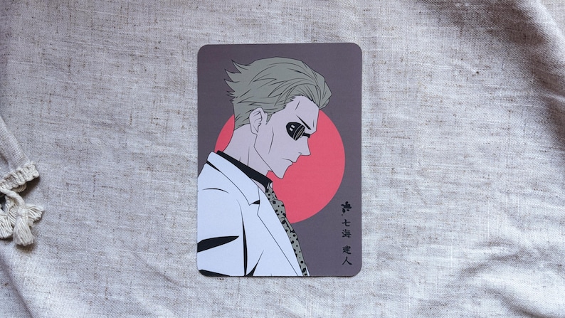 May include: A rectangular card featuring an anime-style illustration of a man in a white suit and sunglasses. The background is a dark gray with a red circle. Japanese text is visible on the right side of the card.