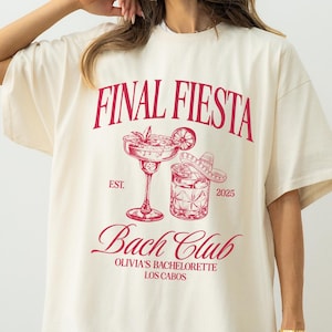 May include: Ivory tee shirt with a red graphic that reads "FINAL FIESTA Bach Club" with margarita and sombrero illustrations. The text "OLIVIA'S BACHELORETTE LOS CABOS" is also included. The shirt is a relaxed fit.