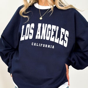 May include: A navy blue sweatshirt with white text that reads "Los Angeles, California".