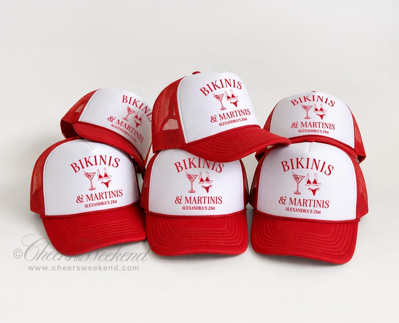 May include: A stack of red and white trucker hats. The hats have a red brim and mesh back, with a white front panel. The front panel of each hat displays the text "BIKINIS & MARTINIS" in red, along with a martini glass and bikini graphic.
