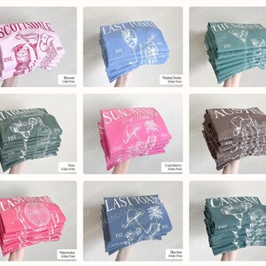 Pu&ograve; includere: Una collezione di nove magliette piegate in vari colori, tra cui rosa, blu, verde e marrone. Ogni maglietta presenta una stampa grafica unica in bianco o avorio con testo come Scottsdale, Last Toast, Margarita, Sun Sandy & A Drink, Austin e Cancun.