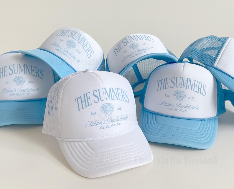 May include: White trucker hats with light blue brims and mesh backs. The hats feature the text "THE SUMNERS" in light blue, along with "Ashton's Bachelorette" and "OAK ISLAND, NC". A seashell graphic is also included.