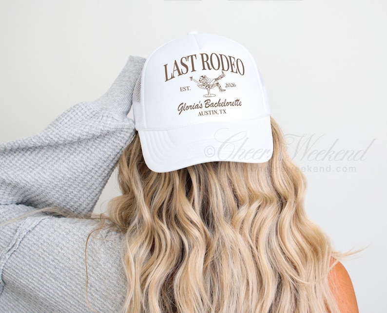 May include: White trucker hat with the text "LAST RODEO" in brown, along with a graphic of a person in a cowboy hat. The hat also includes the text "Gloria's Bachelorette, Austin, TX".