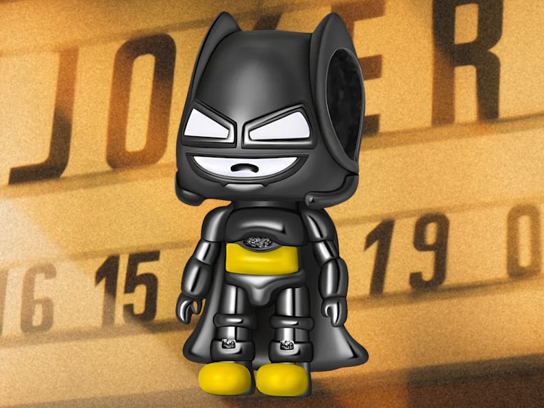May include: Black and yellow Batman character charm with a black cape and a yellow chest piece. The charm is in a cartoon style and has a wide smile.