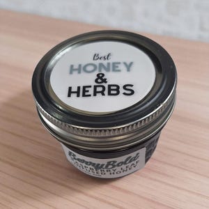 Glass honey jar with herbal infusion, shown from top-front angle