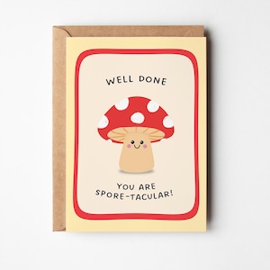 Puede incluir: Tarjeta de felicitación con una ilustración de un hongo de dibujos animados. El hongo tiene un sombrero rojo con lunares blancos y una cara sonriente. El texto dice "WELL DONE" y "YOU ARE SPORE-TACULAR!"