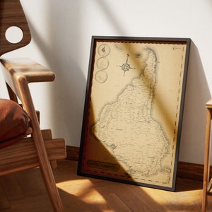 Peut inclure: Carte vintage encadrée de l'Amérique du Sud, avec un design cartographique détaillé en tons sépia. La carte comprend une rose des vents et est encadrée dans un cadre noir. L'œuvre est appuyée contre un mur blanc à côté d'une chaise en bois.