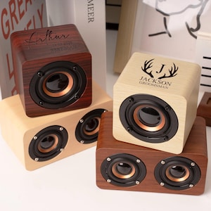 May include: Wooden cube speakers in shades of brown and tan, featuring black speaker cones and copper accents. Some speakers have personalized text, including names and dates. The speakers are stacked on top of each other.