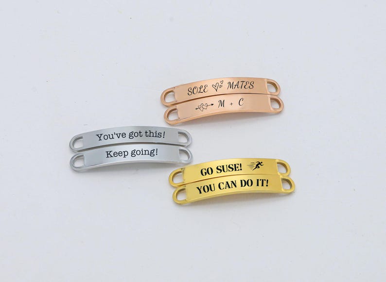 May include: Three gold shoe charms with different messages. The first charm says "Sole Mates" with a heart symbol and the initials "M + C". The second charm says "You've got this! Keep going!" The third charm says "Go Suse!" with a running figure and "You can do it!"