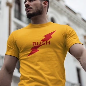 May include: A yellow t-shirt with a red lightning bolt graphic and the word "RUSH" printed on the front.
