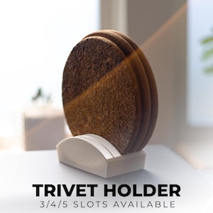May include: A set of round, brown trivets made of cork, displayed in a white holder. The trivets are stacked vertically, showcasing their textured surface. The holder has a curved design. Text at the bottom reads "TRIVET HOLDER 3/4/5 SLOTS AVAILABLE."