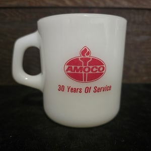 Puede incluir: Taza de café de cerámica blanca con un logotipo de Amoco rojo y el texto "30 Years Of Service".