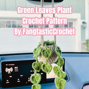 May include: A handmade crochet plant with green leaves, hanging from a car's rearview mirror. The plant pot is beige and the leaves are a vibrant green. Text on the image reads "Green Leaves Plant Crochet Pattern By FangtasticCrochet" and "PDF File".