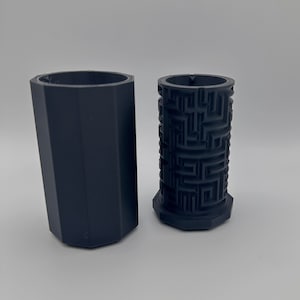 May include: Two black 3D printed containers, one with a smooth surface and the other with a maze pattern.