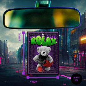 May include: A black car air freshener with a green "RELAX" graphic and a gray teddy bear holding a red heart. The air freshener is 3 inches wide and 4 inches tall.
