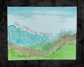May include: Watercolor painting with a landscape scene in shades of blue, green, and brown. The text "The LORD is my shepherd; I shall not want. Psalm 23:1" is handwritten across the top and bottom of the image.