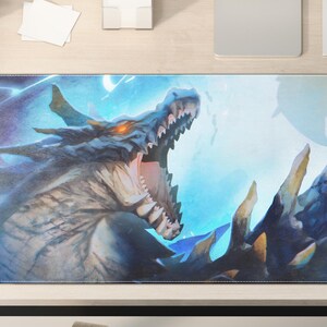 Può includere: Tappetino per scrivania rettangolare con un'illustrazione dettagliata di un drago blu con la bocca aperta, sullo sfondo di fulmini e cielo blu. I denti e gli artigli del drago sono dorati. Il tappetino è su una scrivania in legno chiaro.