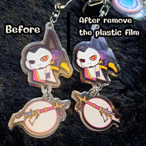 May include: Two clear acrylic keychains with a cartoon character holding a weapon. The keychain on the left has a protective plastic film on it, while the keychain on the right has the film removed. The text "Before" is on the left and "After remove the plastic film" is on the right.