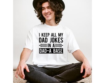 May include: White t-shirt with black text that reads "I keep all my dad jokes in a dad-a base".