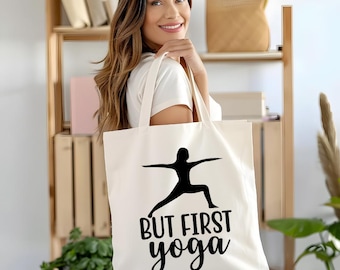 May include: A white canvas tote bag with a black silhouette of a person doing yoga and the text "But First Yoga".