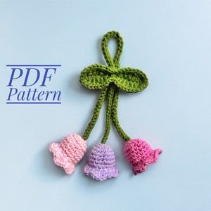 May include: A crochet pattern for a flower bouquet with three pink and purple flowers and green leaves. The pattern is available as a PDF download. PDF Pattern