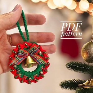 May include: A green and red crocheted Christmas wreath ornament with a gold bell and tartan ribbon. PDF pattern.