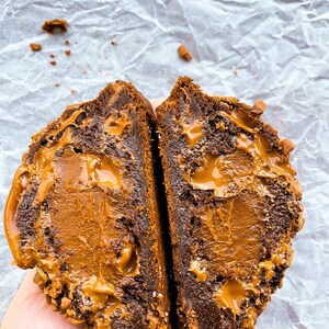 May include: Close-up of a chocolate cookie broken in half, revealing a gooey caramel filling.