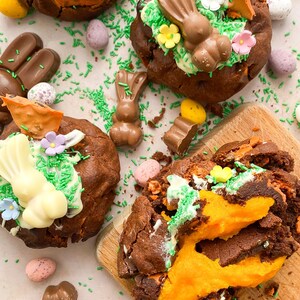 Pode incluir: Vista a&eacute;rea de sobremesas de chocolate com tema de P&aacute;scoa. Os doces s&atilde;o decorados com coelhinhos de chocolate, granulado verde e flores coloridas. Ovos de chocolate e chocolates em forma de coelho est&atilde;o espalhados.