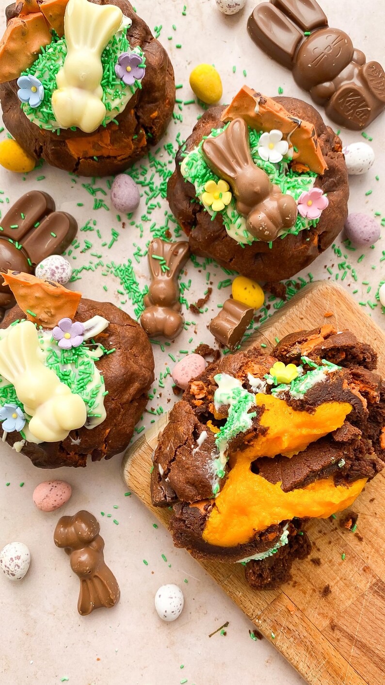 Pode incluir: Vista a&eacute;rea de sobremesas de chocolate com tema de P&aacute;scoa. Os doces s&atilde;o decorados com coelhinhos de chocolate, granulado verde e flores coloridas. Ovos de chocolate e chocolates em forma de coelho est&atilde;o espalhados.