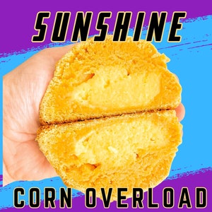 Könnte beinhalten: Nahaufnahme eines halbierten süßen Maisbrotbrötchens, gefüllt mit einer hellgelben Maiscreme. Das Brötchen wird in einer Hand gehalten und der Text "SUNSHINE CORN OVERLOAD" ist sichtbar.