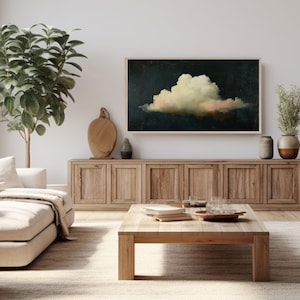 Puede incluir: Una gran pintura abstracta de una nube blanca sobre un fondo azul oscuro. La pintura est&aacute; colgada en una pared sobre un armario de madera y una mesa de caf&eacute;.