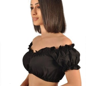 以下が含まれることがあります： 黒色のオフショルダークロップトップ。ネックラインにフリル、短いパフスリーブが特徴です。滑らかな生地で作られており、肩を露出して着用するように設計されています。 この衣服は無地の黒色です。