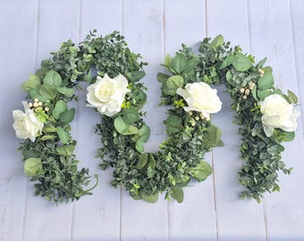 Guirnalda decorativa de rosas artificiales lista para colgar, con follaje y múltiples longitudes, ideal para centros de mesa y decoración del hogar.