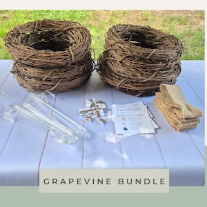 May include: A bundle containing two stacks of brown grapevine wreath bases, several clear plastic wreath hangers, a small pile of white and brown decorative accents, a printed wreath care instruction card, and a folded piece of tan burlap ribbon.